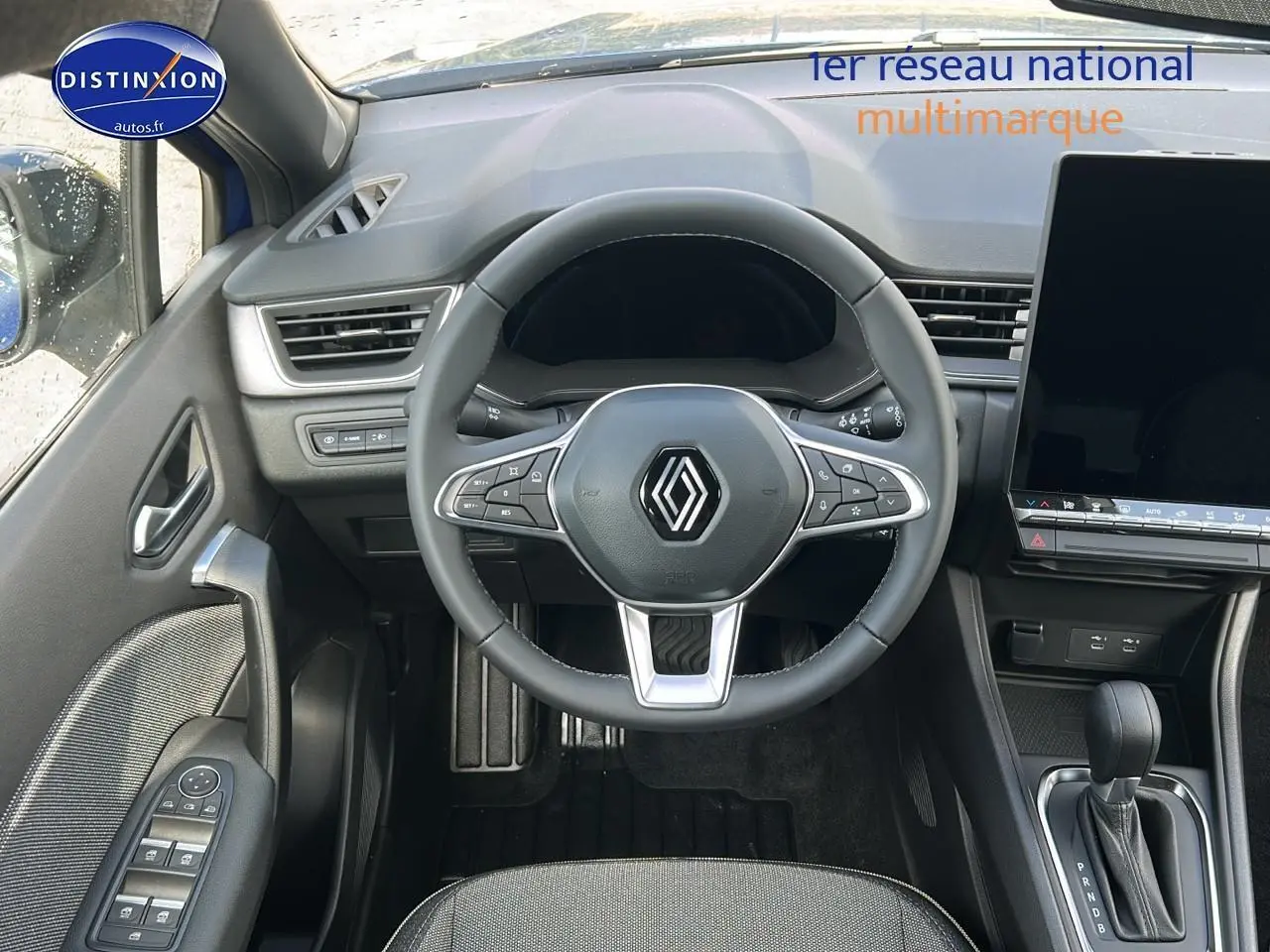 Vue intérieure centrée sur le volant multifonction Renault Captur 1.6 e-tech hybride avec écran tactile et levier de boîte auto.