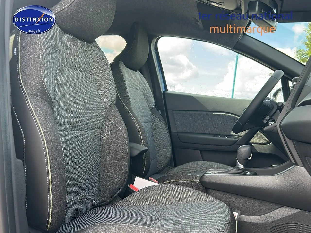 Intérieur avant du Renault Captur 1.6 e-tech hybride 2025, sièges gris avec accoudoir central et levier de boîte automatique.