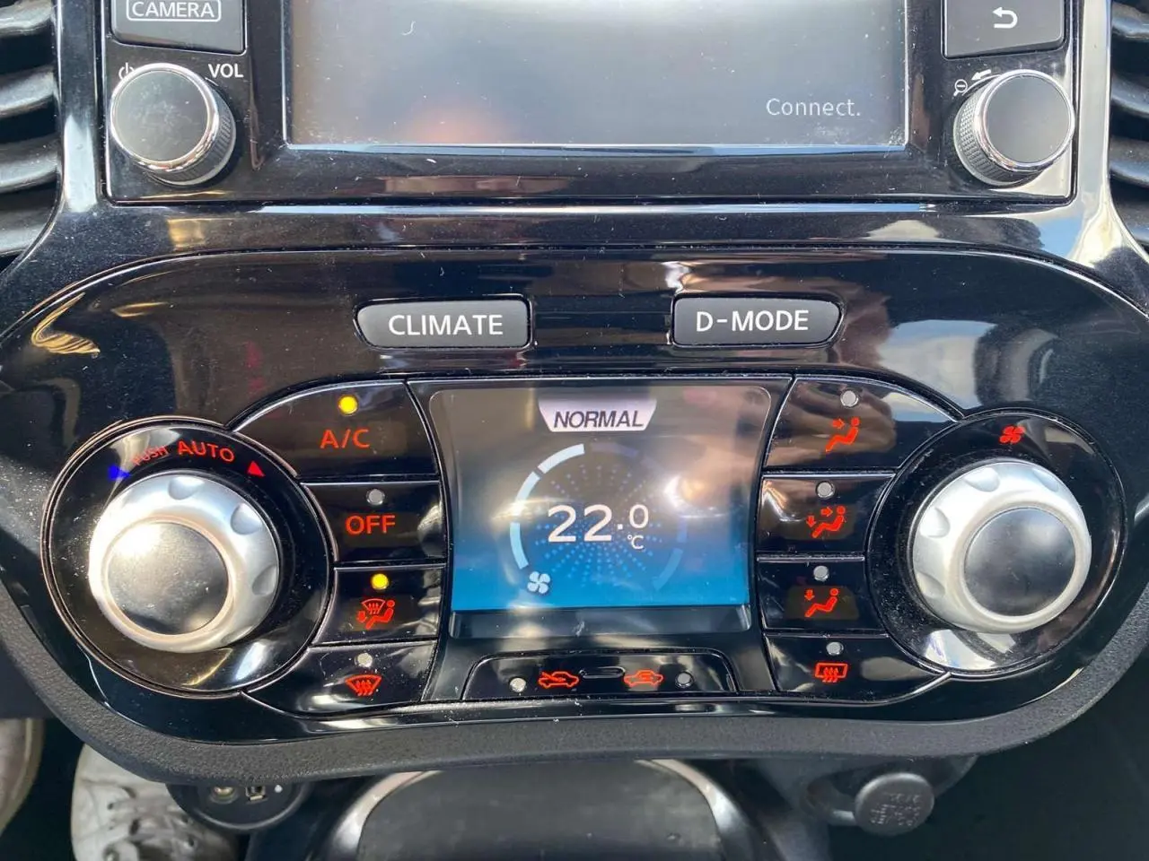 Vue rapprochée de la console centrale du Nissan Juke blanc 2017, affichant la climatisation automatique à 22°C.