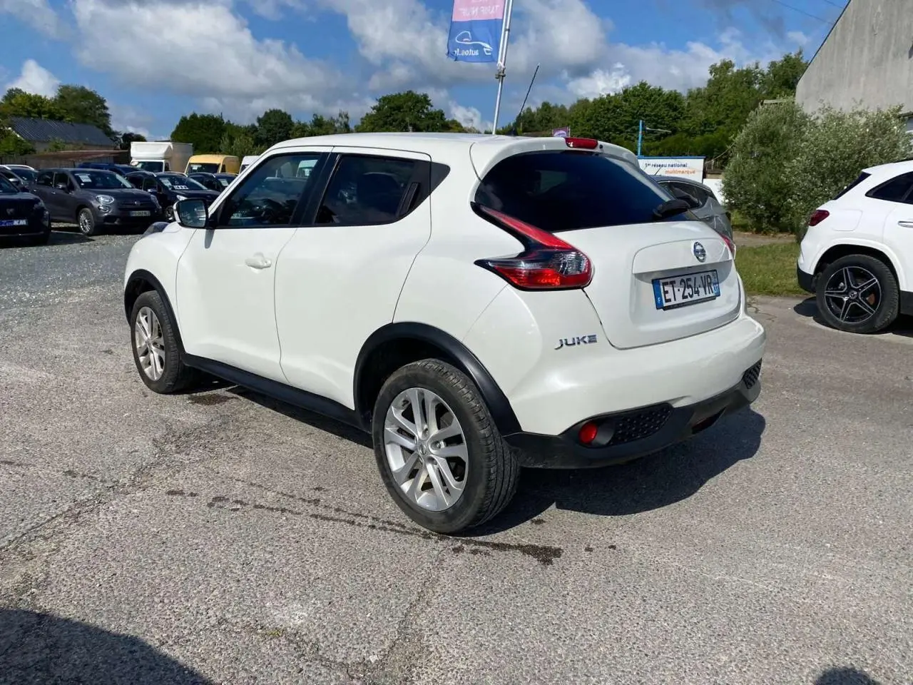 Nissan Juke blanc vue 3/4 arrière droit, vitres arrière surteintées et jantes alliage 17 pouces sport.