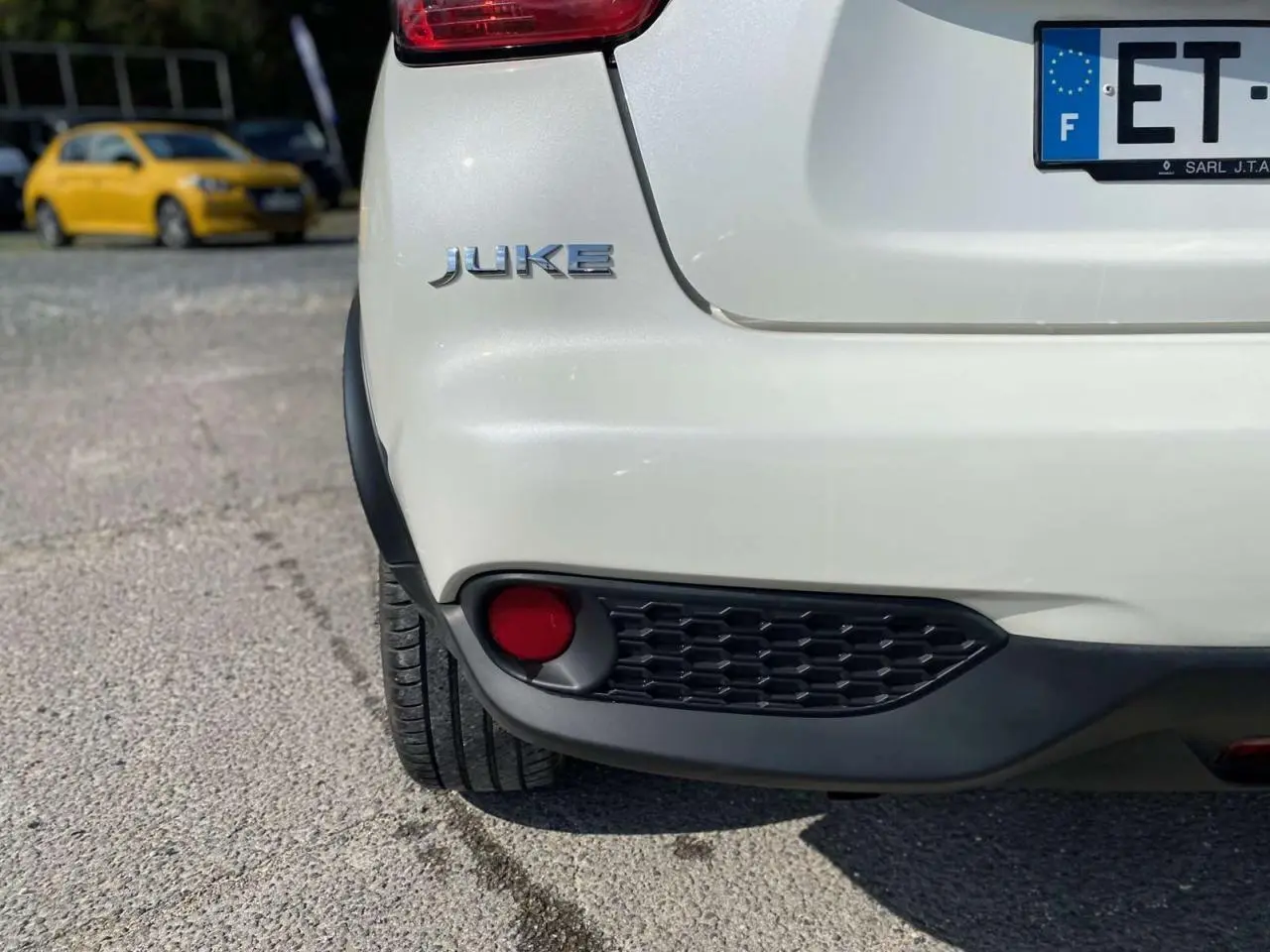 Gros plan sur l'arrière gauche blanc d'un Nissan Juke 2017 avec feu antibrouillard et logo visible.
