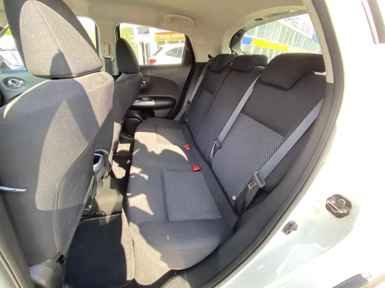 Vue intérieure côté droit sur la banquette arrière noire du Nissan Juke blanc 2017 avec porte ouverte.