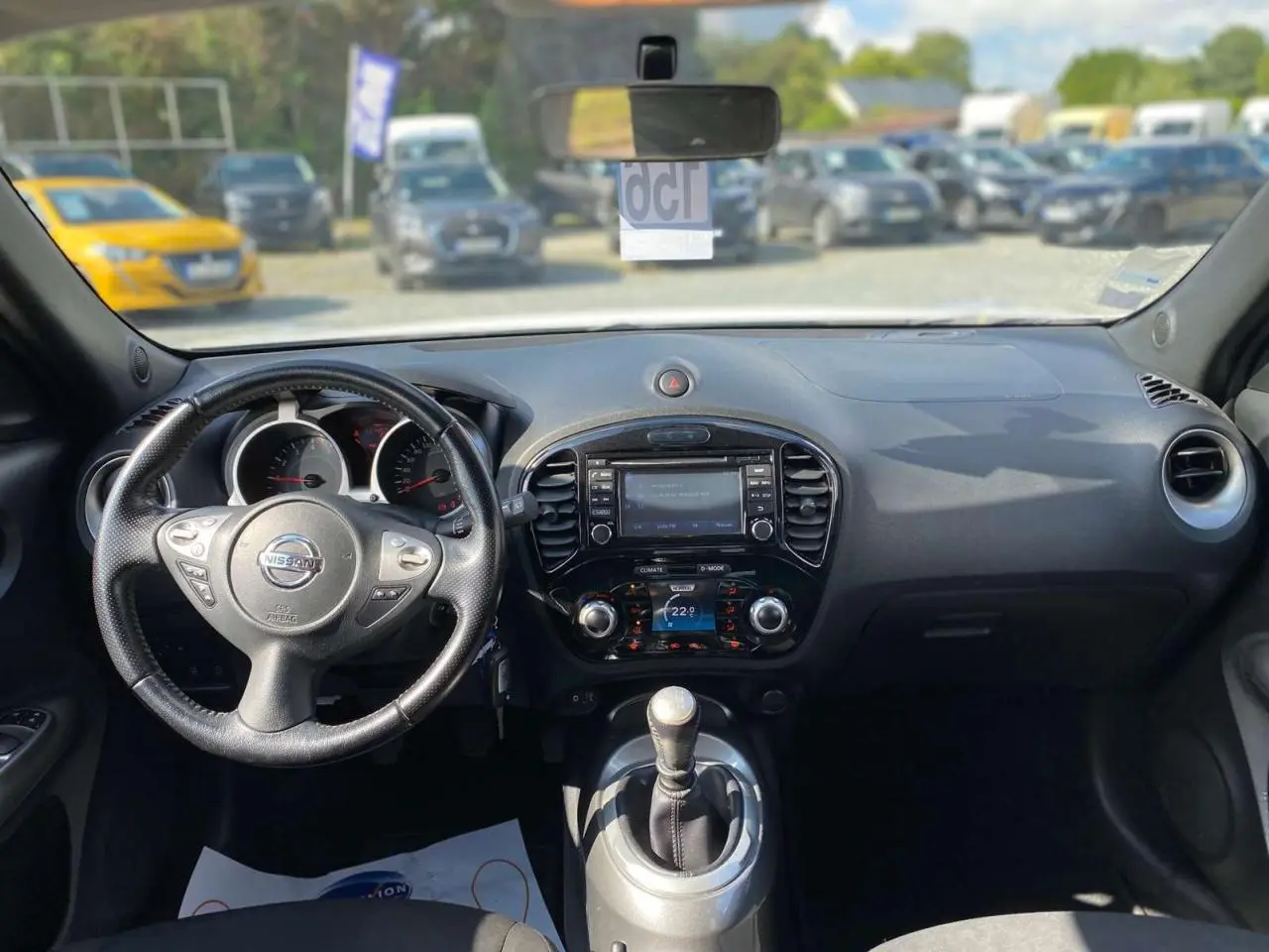 Vue intérieure du tableau de bord et volant du Nissan Juke blanc 2017 avec boîte manuelle et écran central tactile.