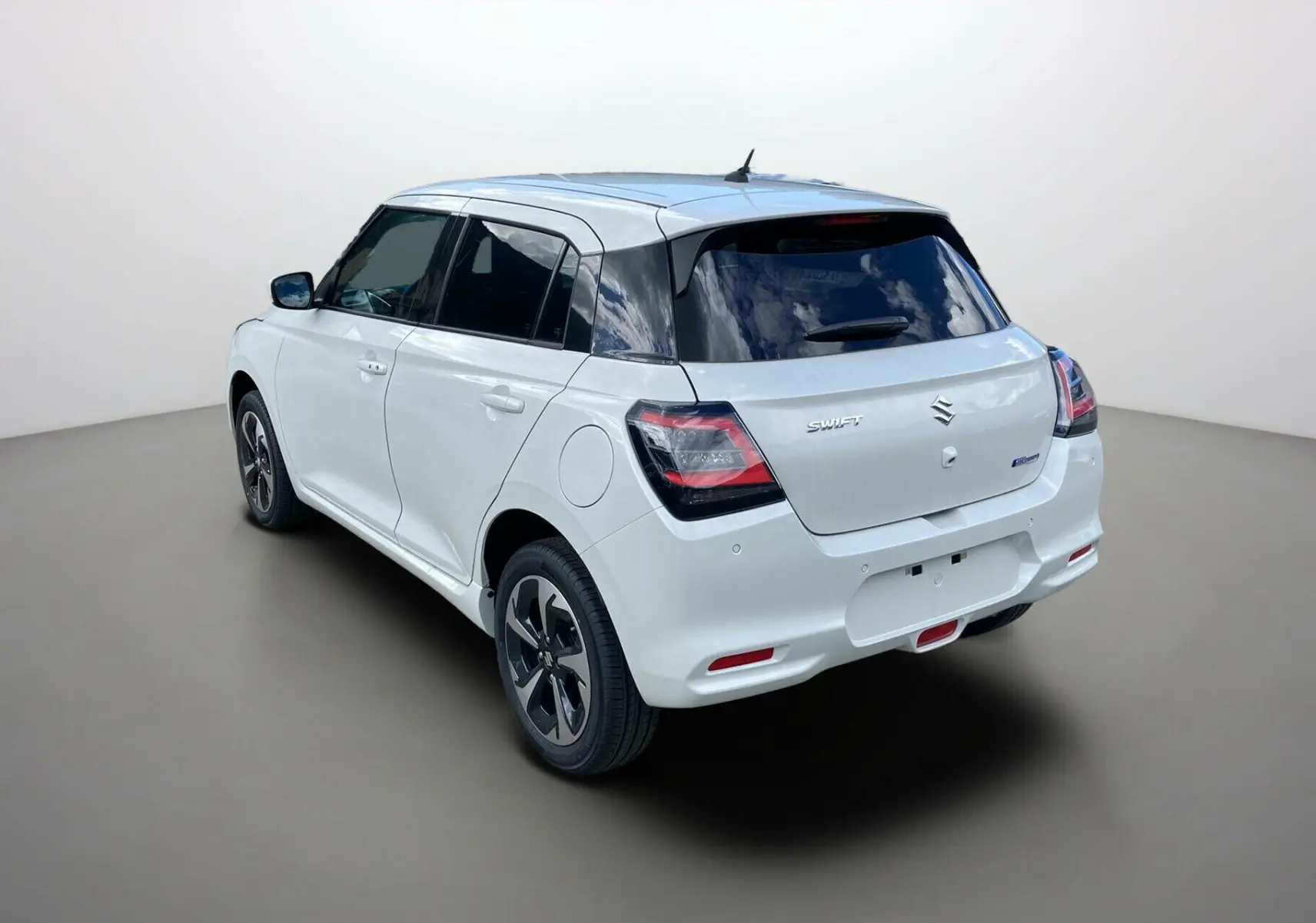 Suzuki Swift 2025 blanche vue 3/4 arrière droit avec vitres surteintées et jantes alu noires.
