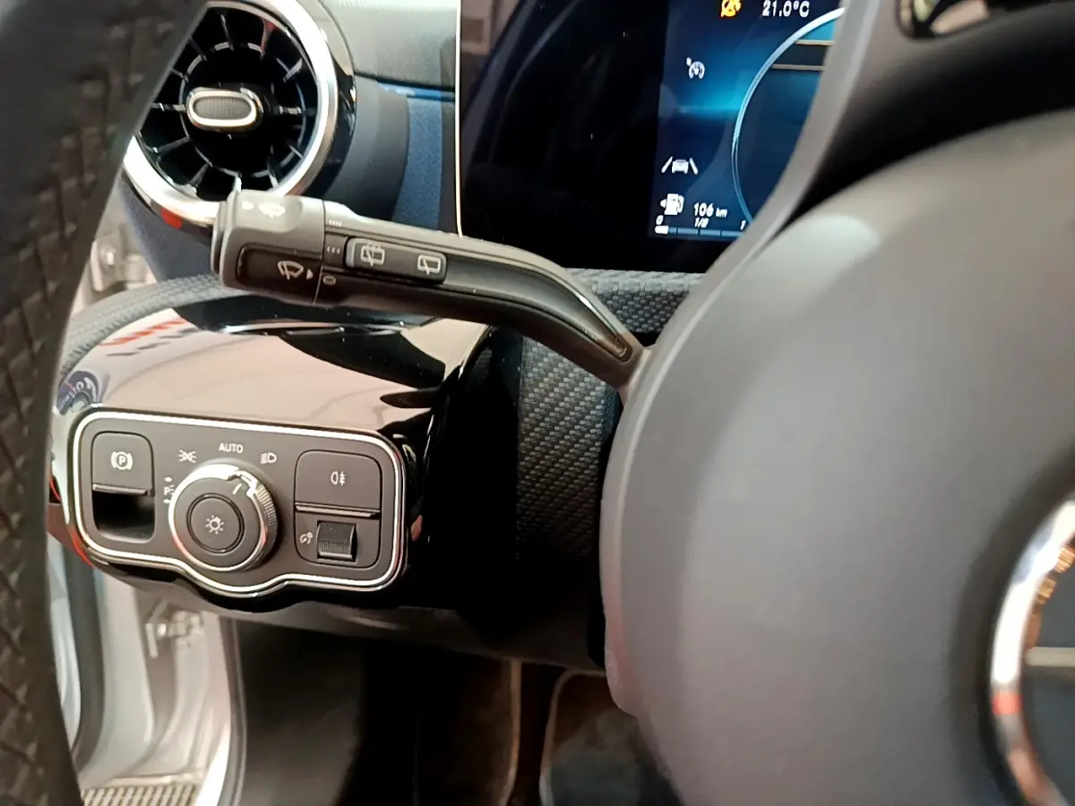 Gros plan sur la commande des phares et le commodo d’essuie-glace côté gauche du tableau de bord gris clair de la Mercedes Classe A 180 d.