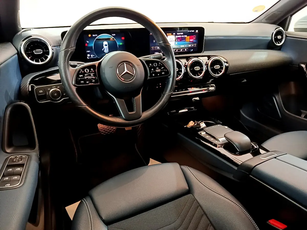 Vue intérieure avant de la Mercedes Classe A 180 d Business Line 2020, tableau de bord noir avec écran tactile et volant cuir.