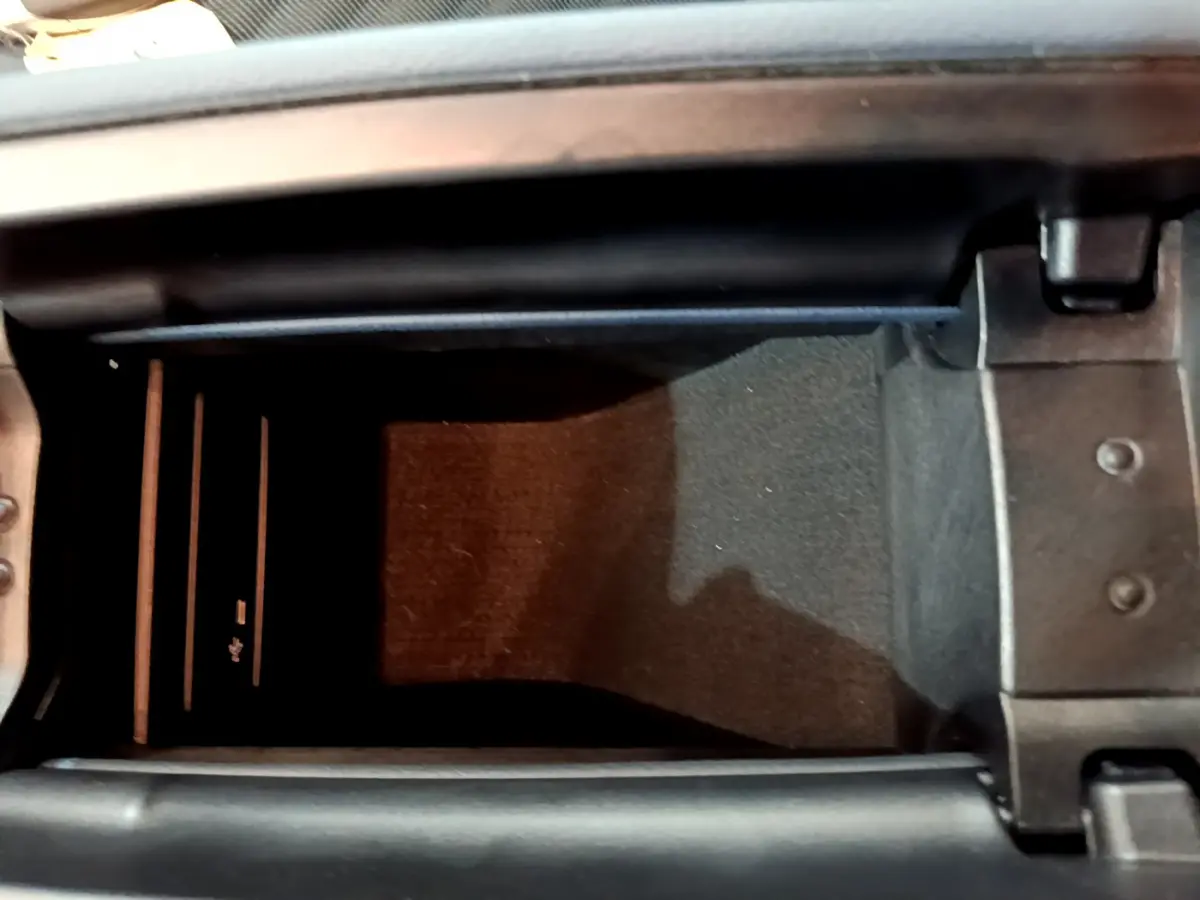 Vue en plongée de la console centrale ouverte d'une Mercedes Classe A gris clair, montrant un espace de rangement intérieur.
