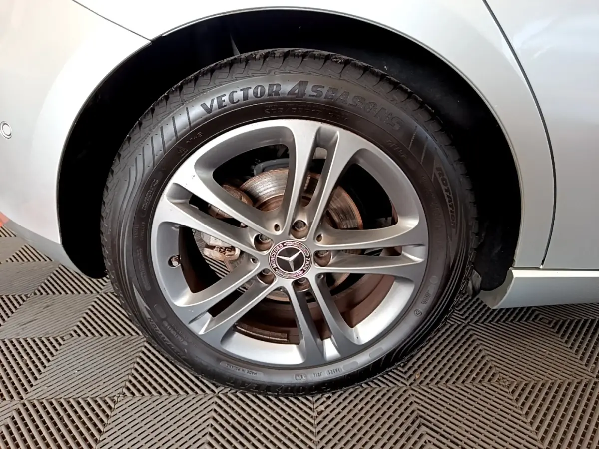 Gros plan sur la roue avant droite gris clair d'une Mercedes Classe A 180 d Business Line avec jante alliage cinq branches.