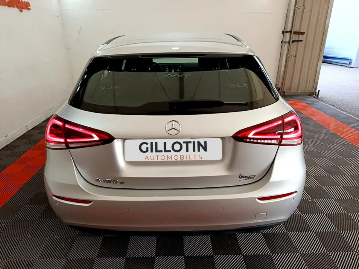 Vue arrière d'une Mercedes Classe A 180 d Business Line gris clair avec feux LED allumés dans un garage.