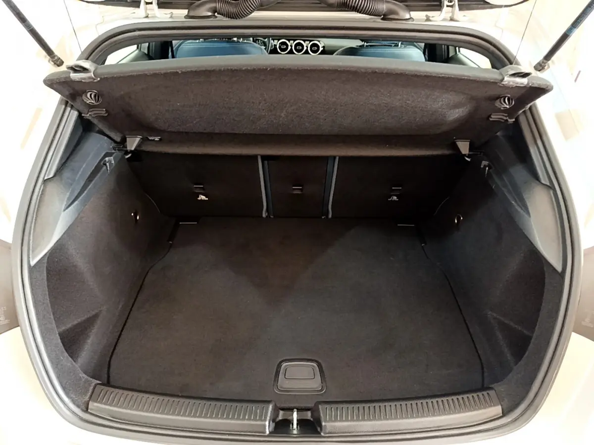 Coffre ouvert vu de l'arrière d'une Mercedes Classe A gris clair, montrant l'espace de chargement vide et la tablette de séparation.