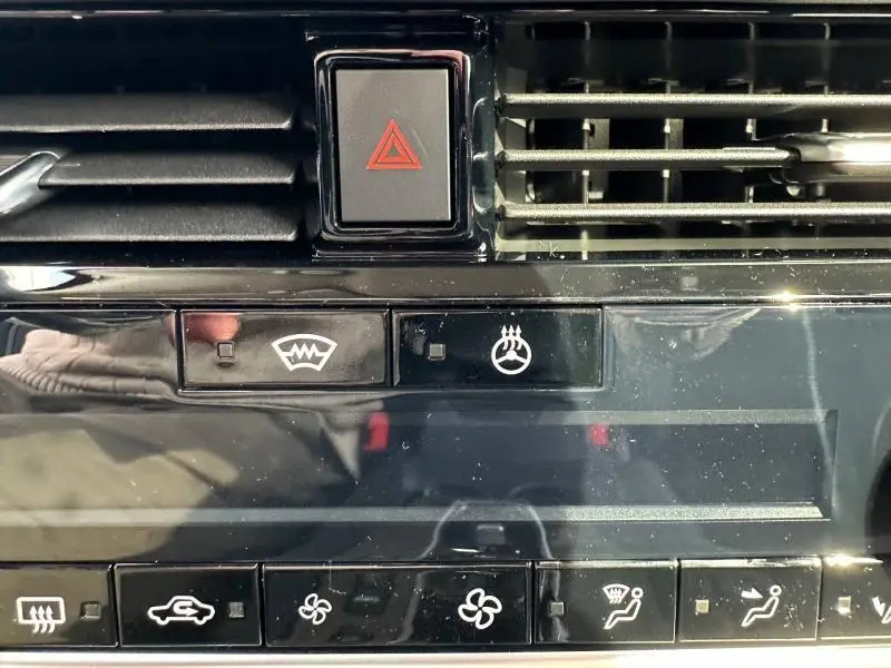 Gros plan sur les commandes de climatisation et bouton de warning du tableau de bord noir brillant du Nissan Qashqai Hybrid e-POWER 2025.