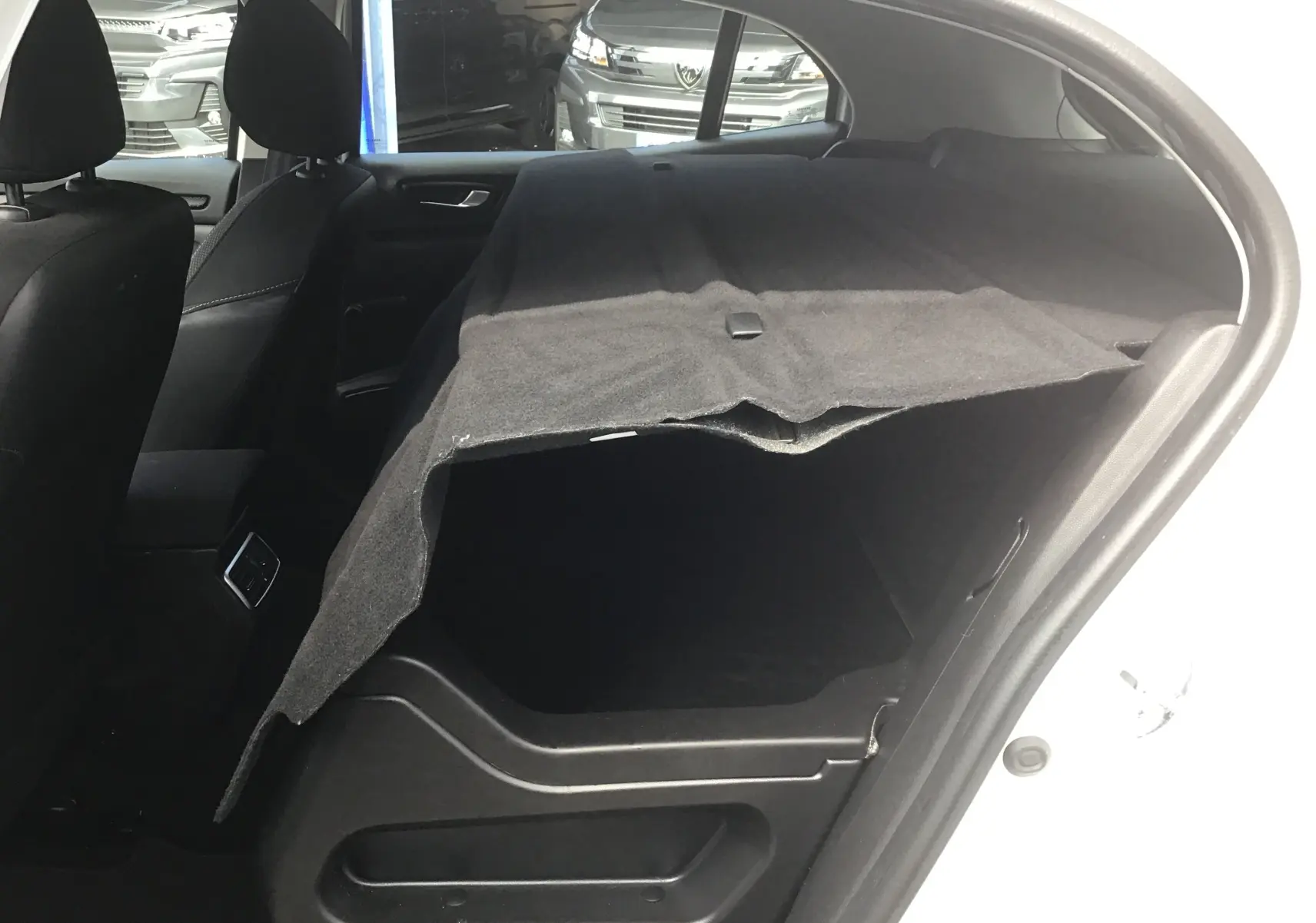 Vue intérieure côté droit du coffre d'une Renault Mégane IV Société blanche, avec cache-bagages déployé.