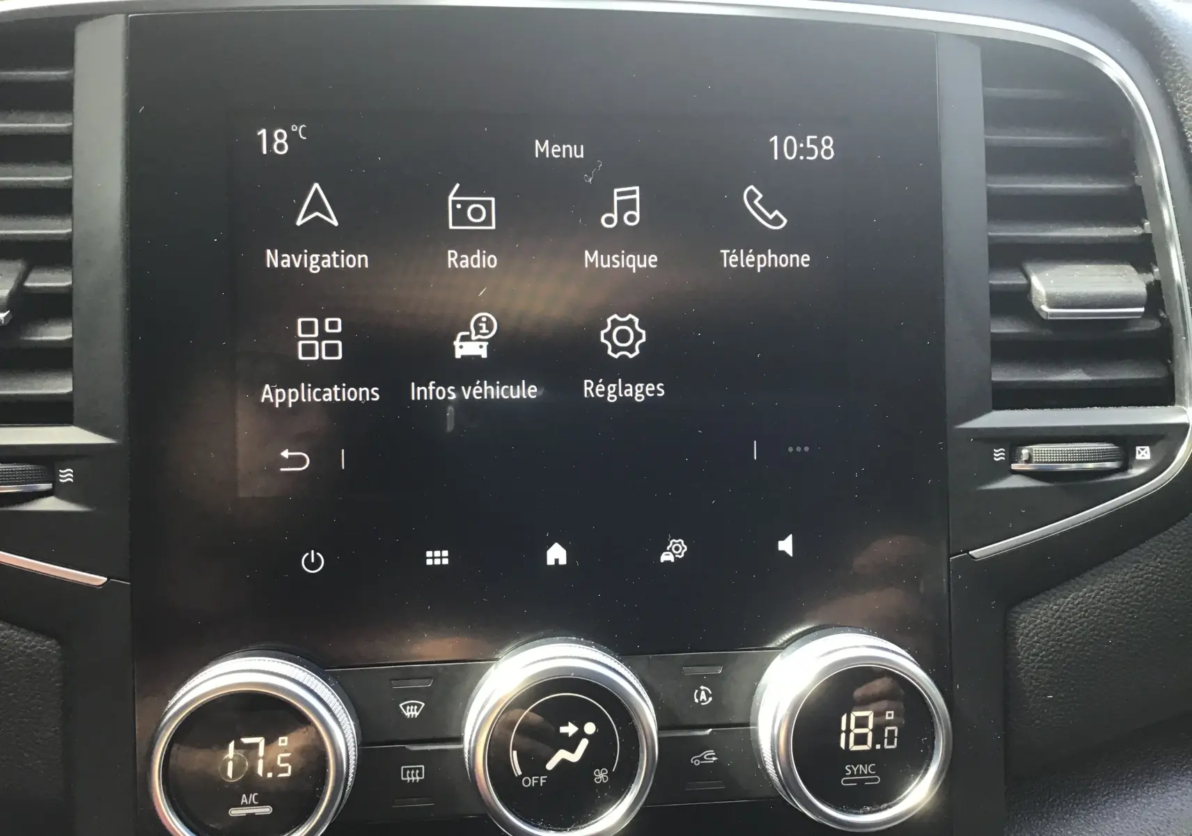 Vue rapprochée de l'écran tactile central et des commandes de climatisation du Renault Mégane IV Société blanc, version 2021.
