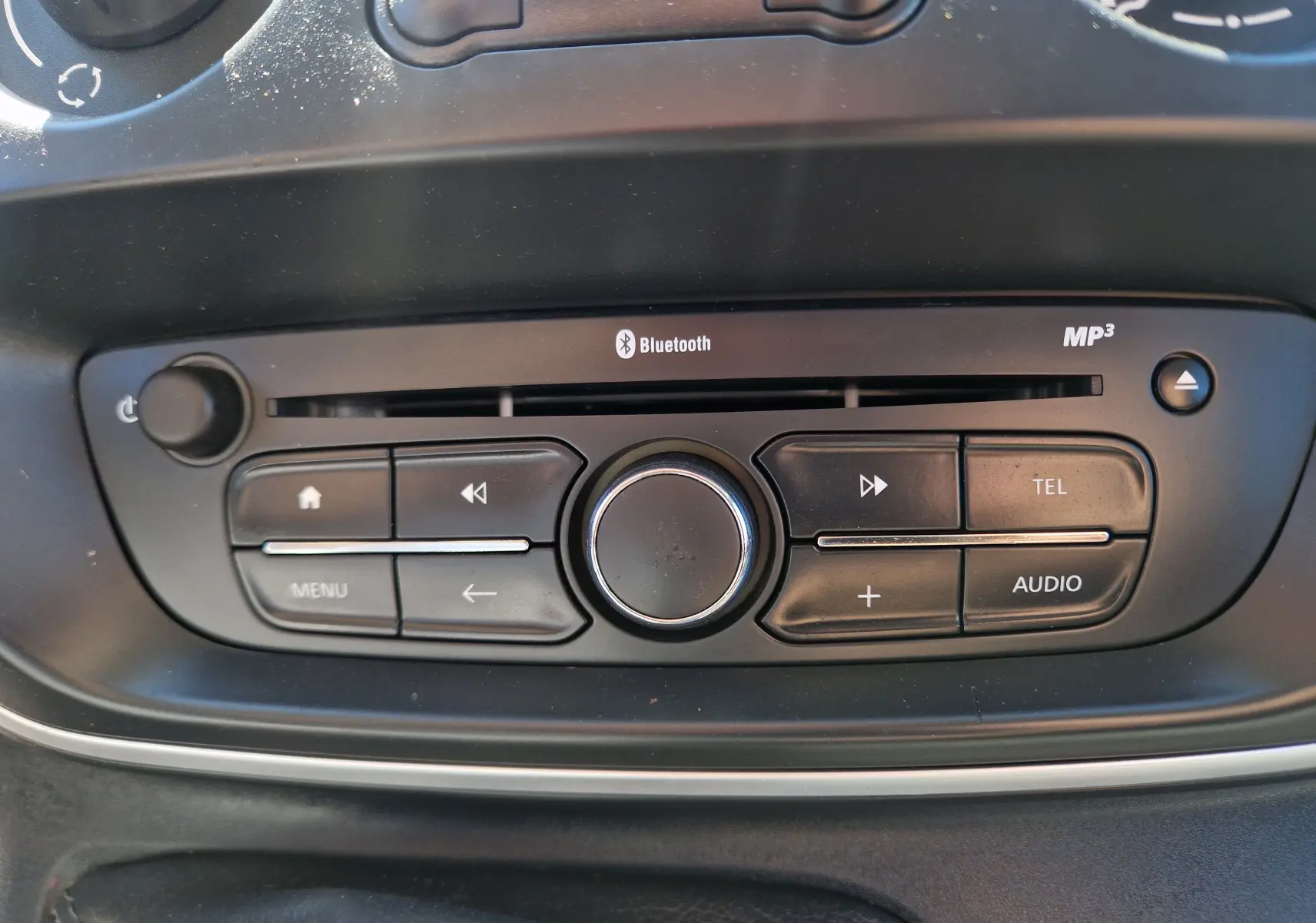 Détail du tableau de bord du Renault Kangoo blanc 2021, montrant les commandes de climatisation et la radio avec Bluetooth.