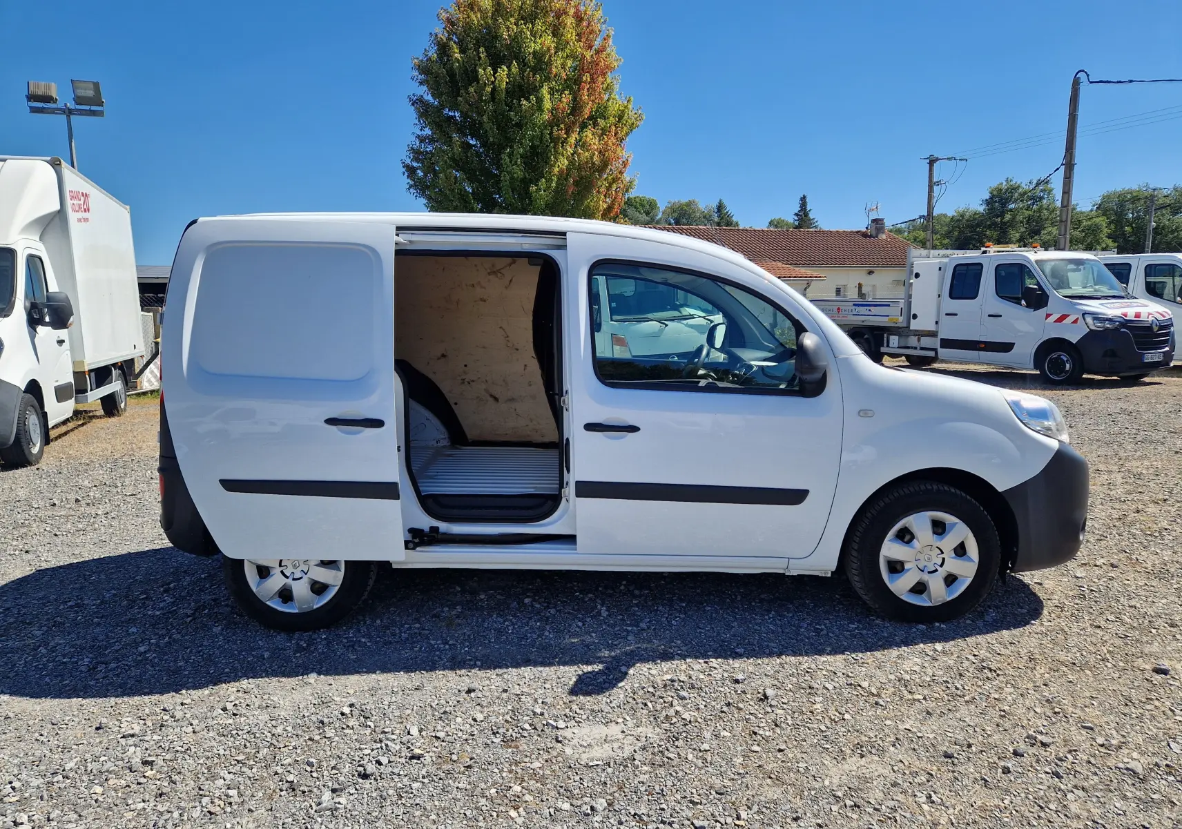 Vue de profil côté droit d'un Renault Kangoo blanc 2021 avec porte latérale coulissante ouverte montrant l'espace de chargement.