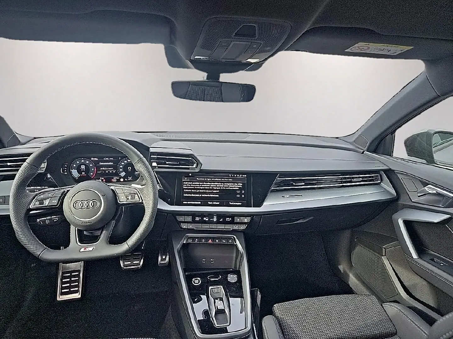 Vue intérieure avant de l'Audi A3 Sportback gris Daytona 2026, volant sport multifonction et écran tactile central.