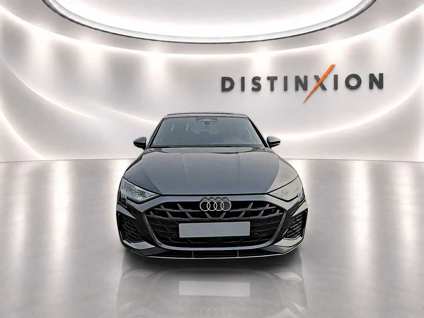 Audi A3 Sportback gris Daytona vue de face dans un studio avec logo Distinxion en arrière-plan.