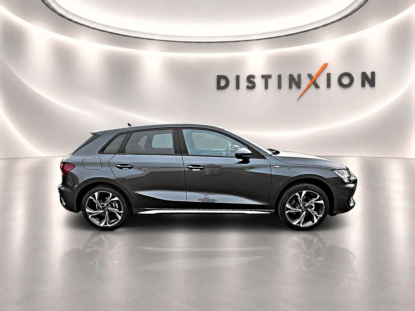 Profil droit d'une Audi A3 Sportback gris Daytona avec jantes alu 18 pouces dans un showroom lumineux.