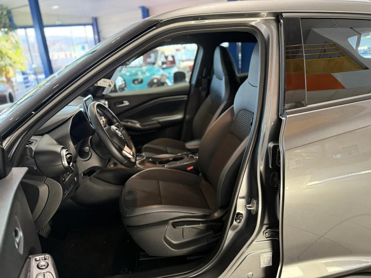 Intérieur côté conducteur du Nissan Juke Hybrid gris métallisé 2024 avec sièges mixte tissu et cuir noir.