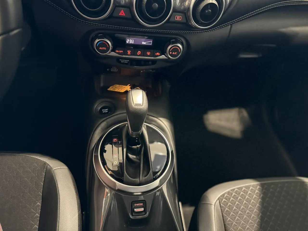 Intérieur du Nissan Juke Hybrid 2024, vue rapprochée sur levier de vitesses automatique et console centrale noire.