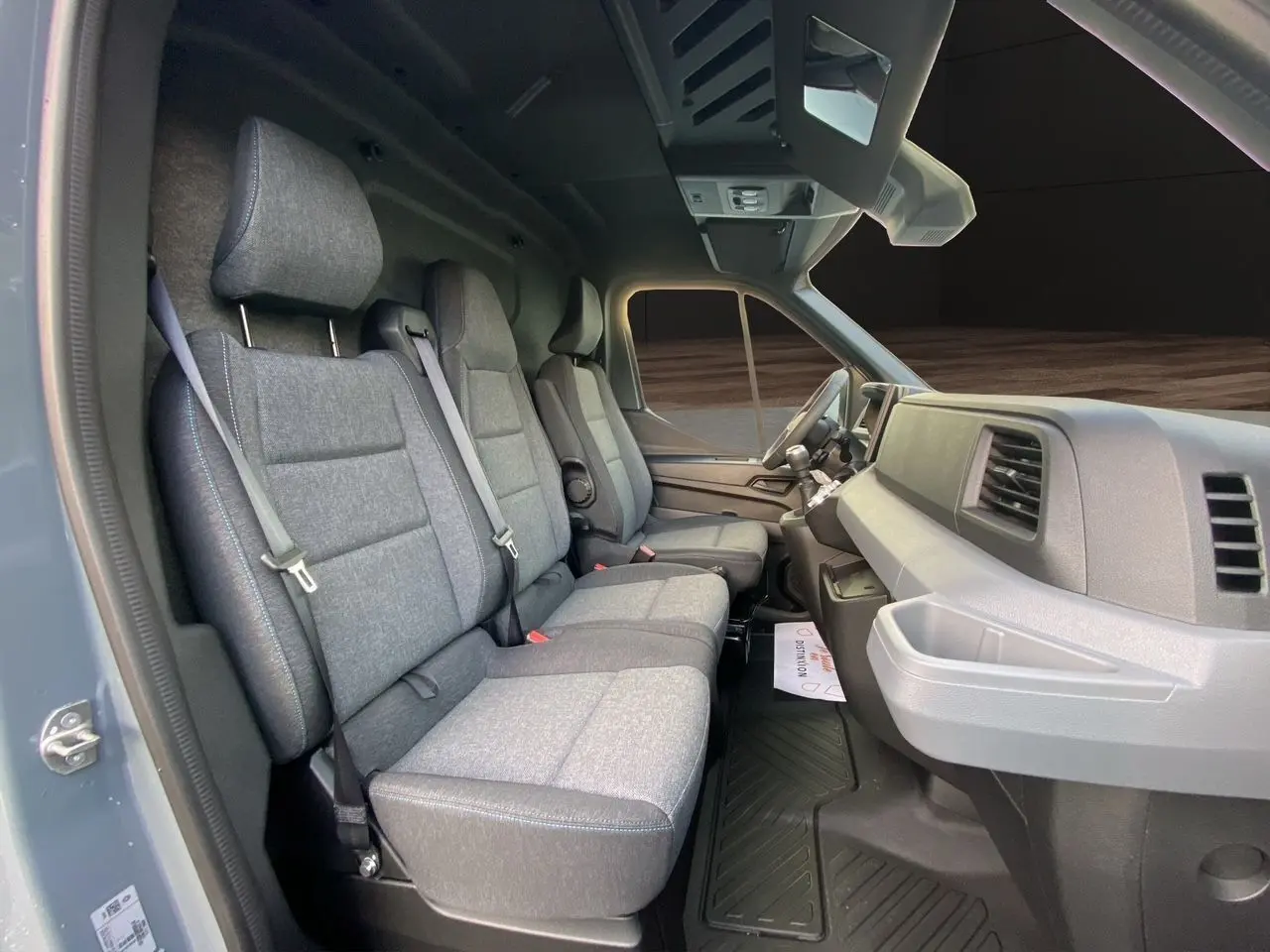 Vue intérieure côté gauche du Renault Master 2025, montrant la banquette passager grise avec surpiqûres bleues et tableau de bord gris.