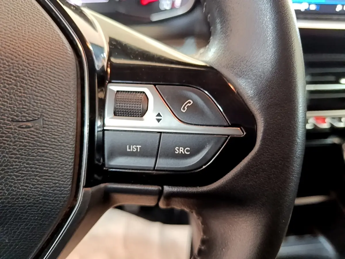 Gros plan sur le volant cuir noir du Peugeot 2008, avec commandes multifonctions côté gauche visibles.