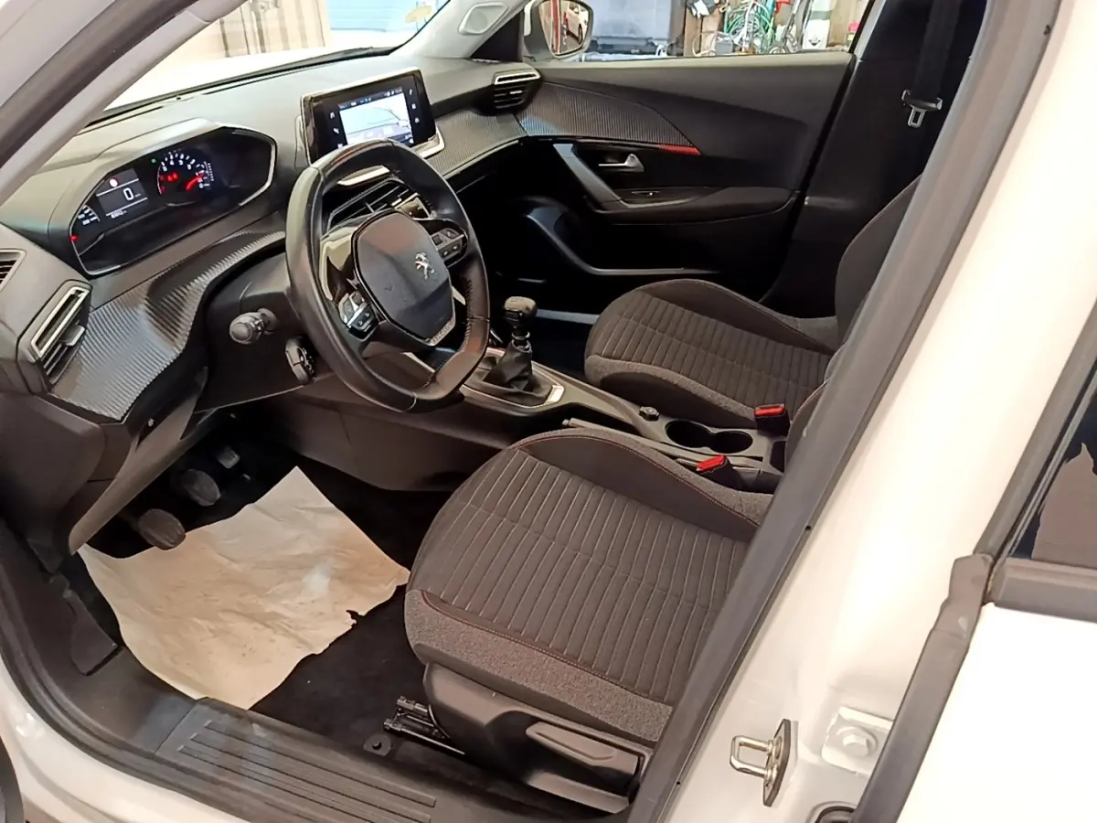 Vue intérieure côté conducteur du Peugeot 2008 blanc 2021, volant cuir multifonctions et tableau de bord numérique.