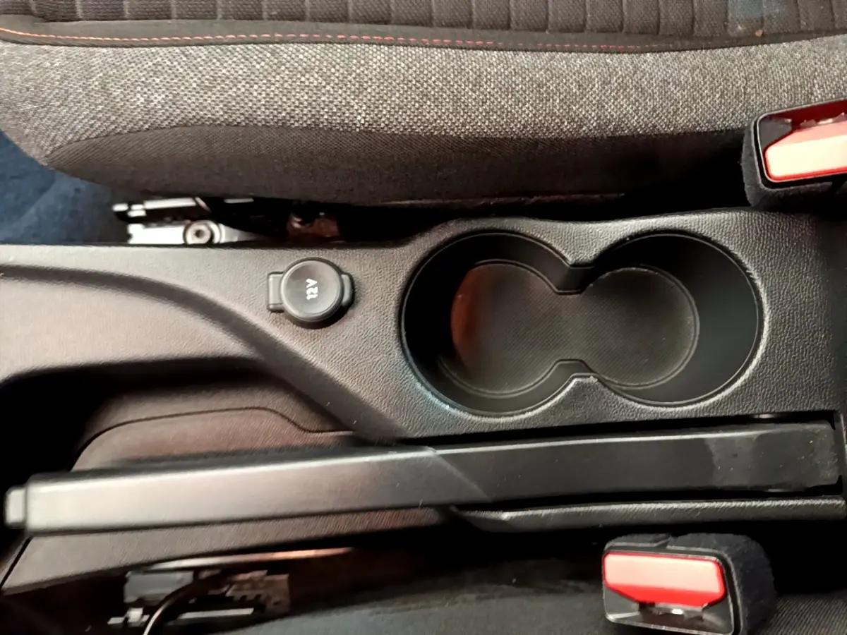 Vue rapprochée de la console centrale noire du Peugeot 2008 avec porte-gobelets et prise 12V.