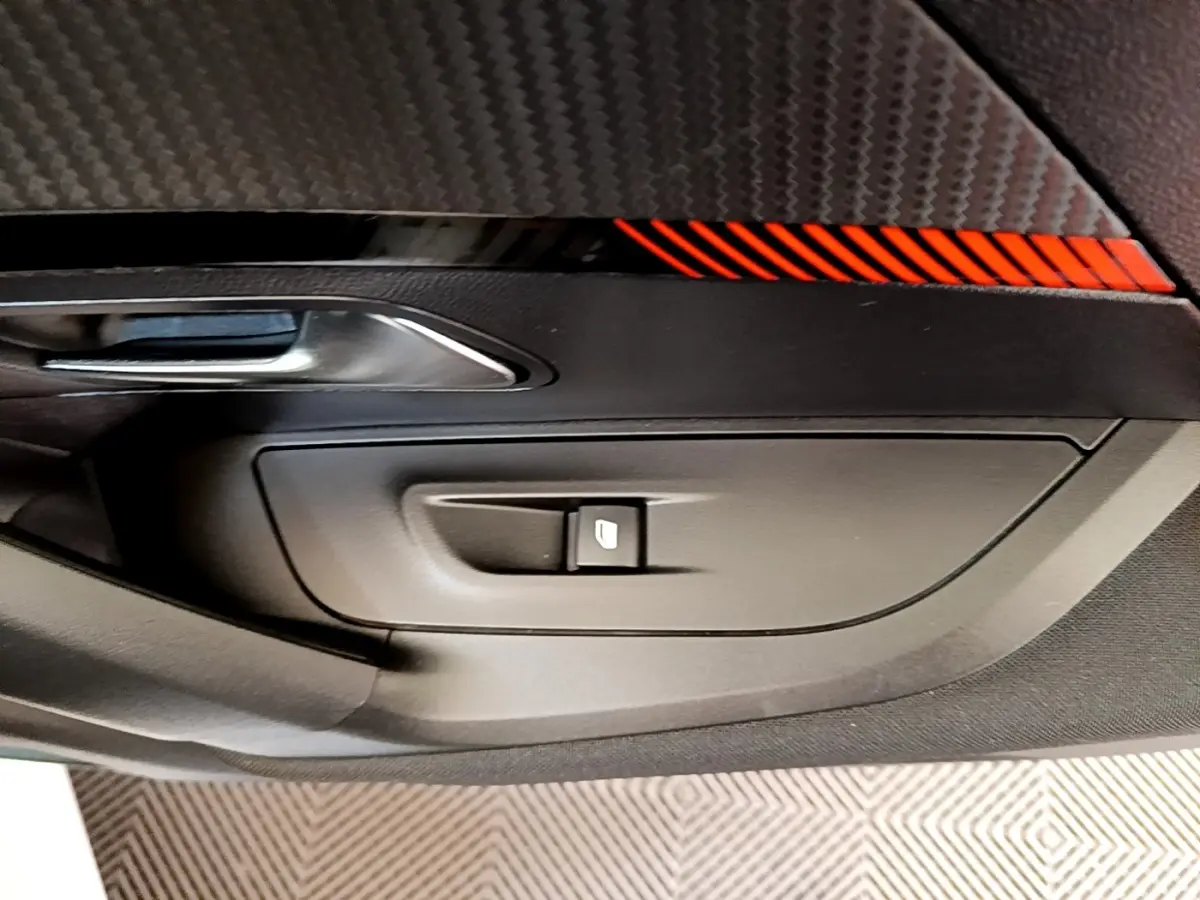 Détail de la porte intérieure côté conducteur du Peugeot 2008 blanc, avec bouton de commande de vitre et insert décoratif rouge.