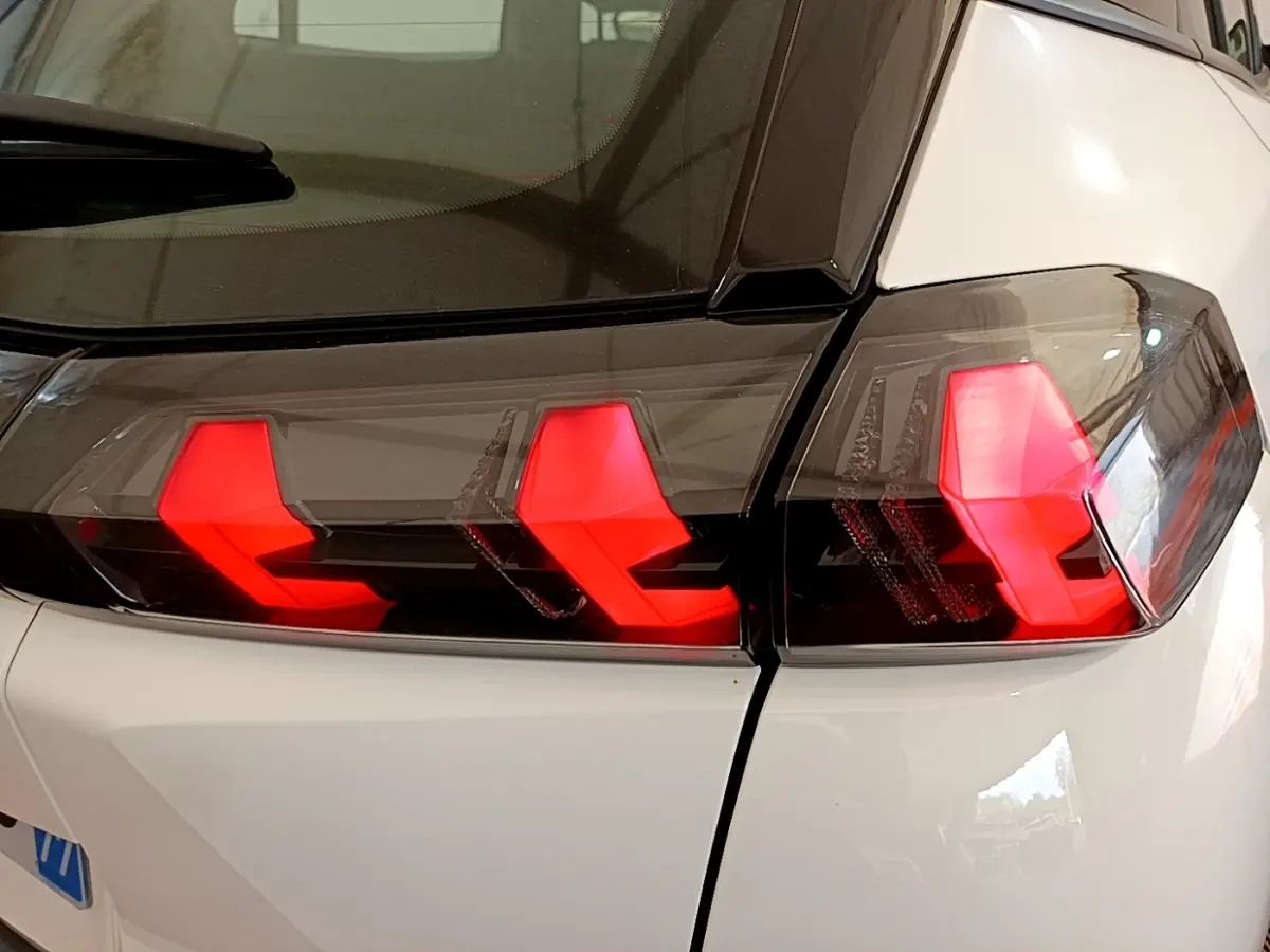 Gros plan sur les feux arrière rouges en forme de griffes du Peugeot 2008 blanc, vue arrière côté droit.