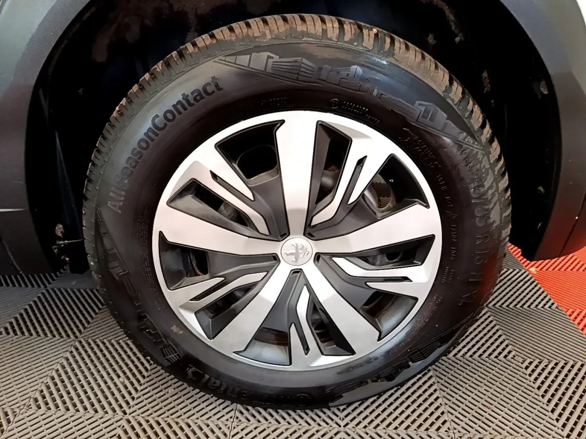 Gros plan sur la roue avant droite de la Peugeot 2008 blanche, avec jante alliage et pneu AllSeasonContact.