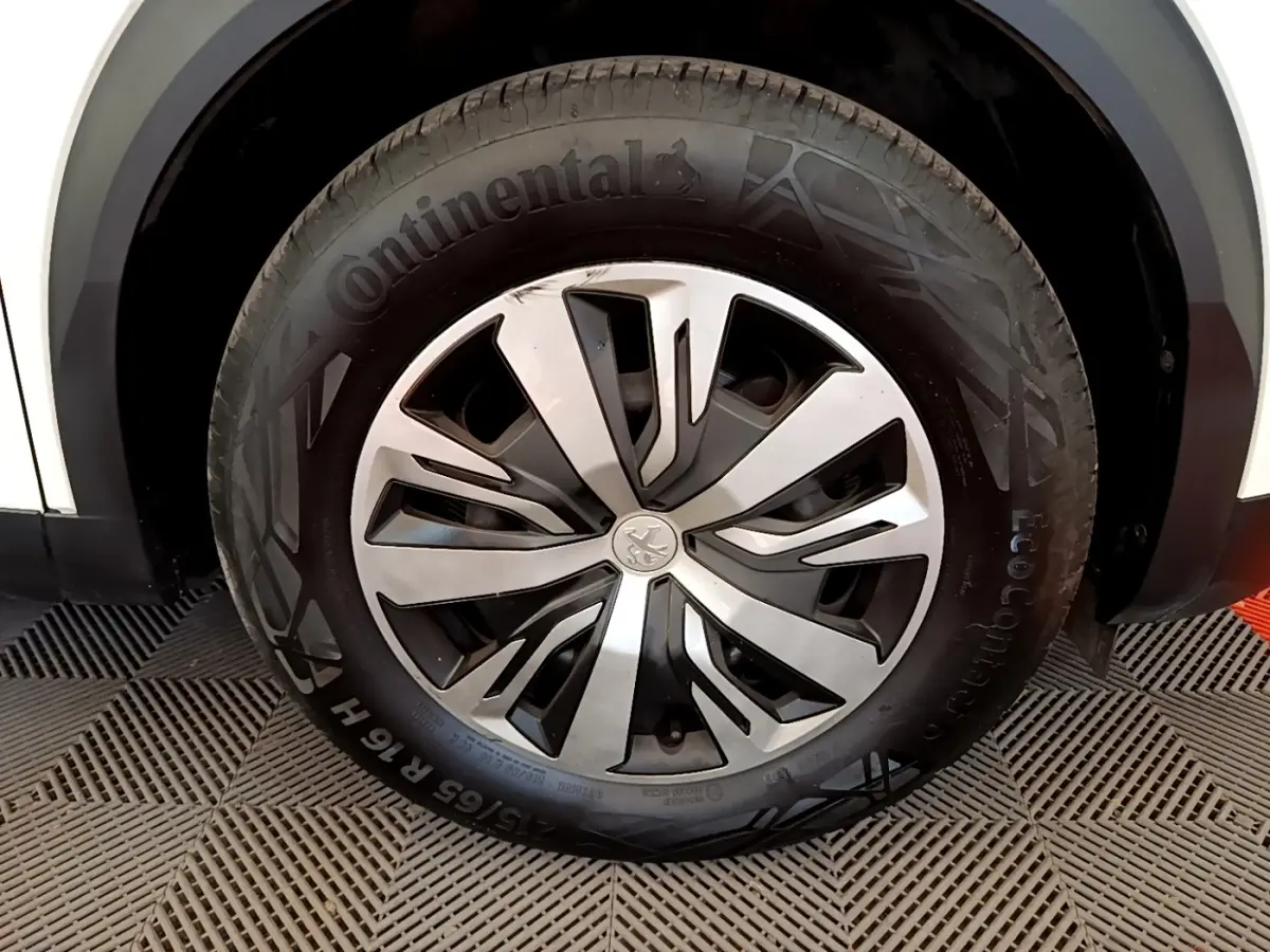 Gros plan sur la roue avant droite d’un Peugeot 2008 blanc, jante alliage à design moderne et pneu Continental.
