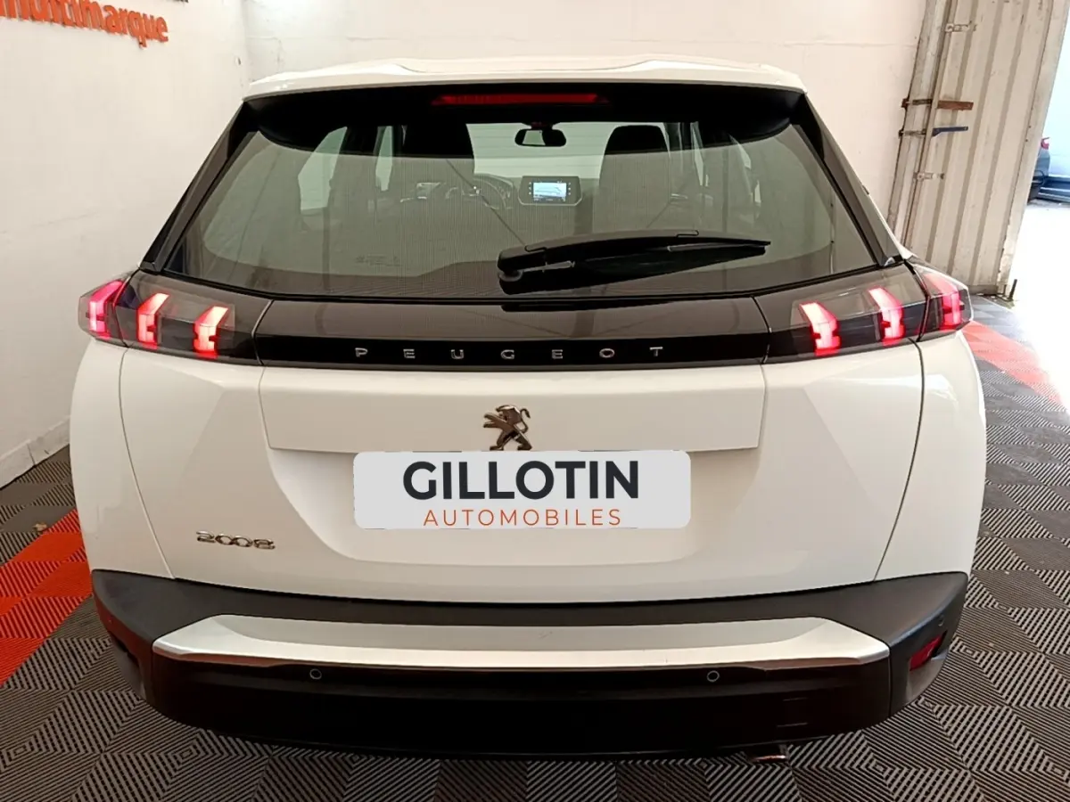 Vue arrière d’un Peugeot 2008 blanc avec feux arrière LED en forme de griffes et logo lion central.
