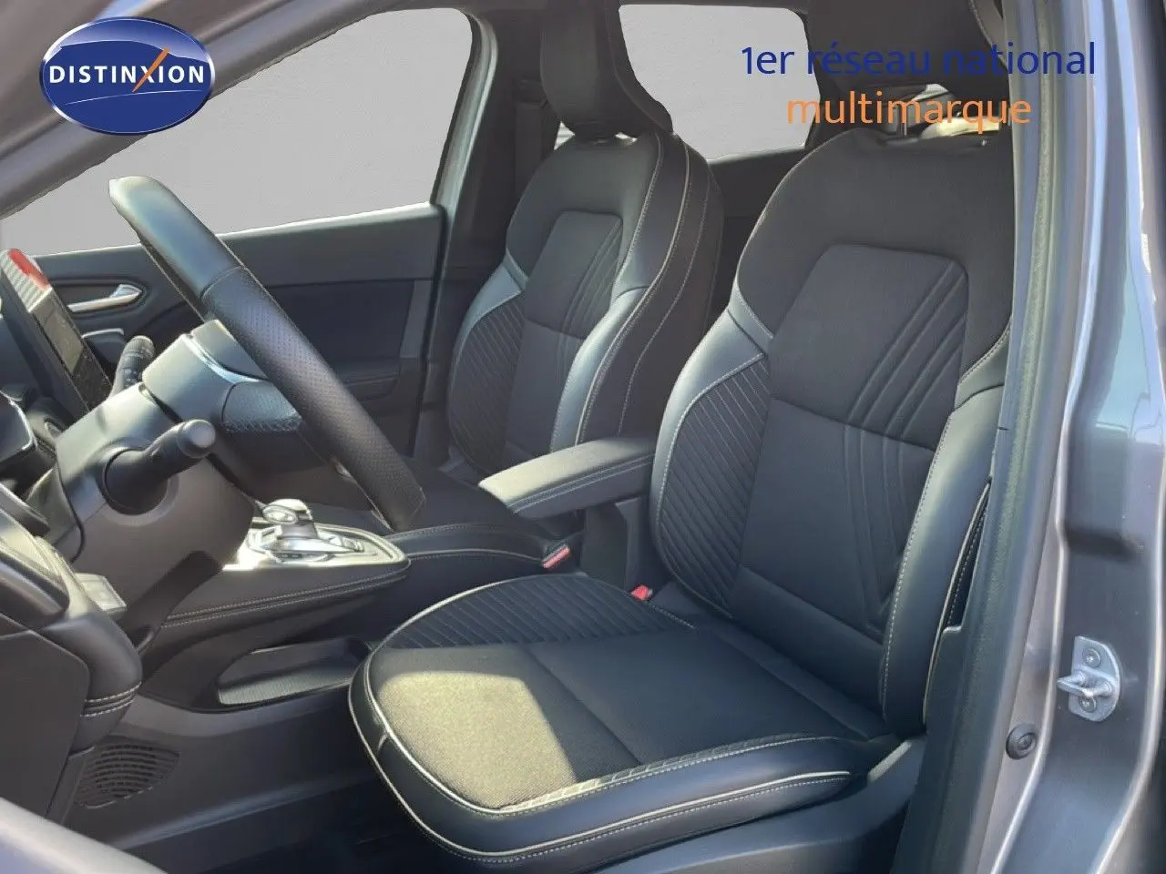 Vue intérieure côté conducteur de la Renault Symbioz 2025 gris cassiopée, sièges noirs en tissu et cuir avec surpiqûres claires.