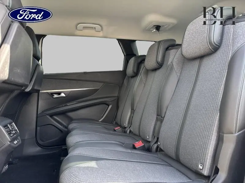Vue intérieure montrant la banquette arrière en tissu gris avec appuis-tête et ceintures de sécurité du Peugeot 5008 blanc nacré.