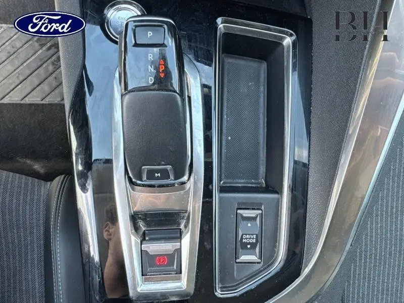 Gros plan sur la console centrale noire brillante avec levier de vitesse automatique et bouton Drive Mode.