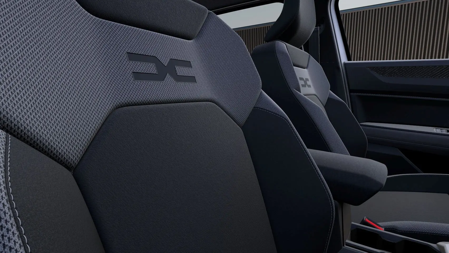 Gros plan sur les sièges avant en tissu gris foncé du Dacia Duster 2026 avec logo distinctif embossé.
