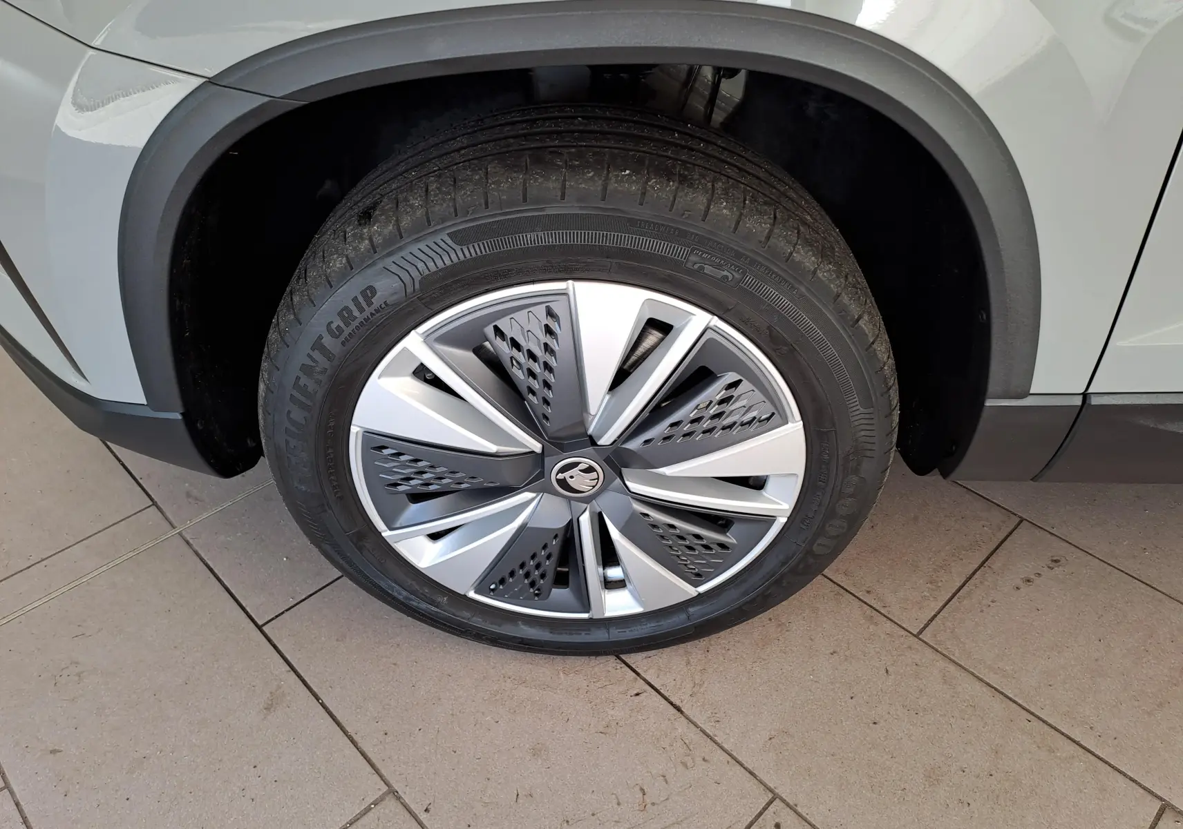 Gros plan sur la roue avant gauche du Skoda Karoq gris perle, mettant en valeur la jante au design moderne.