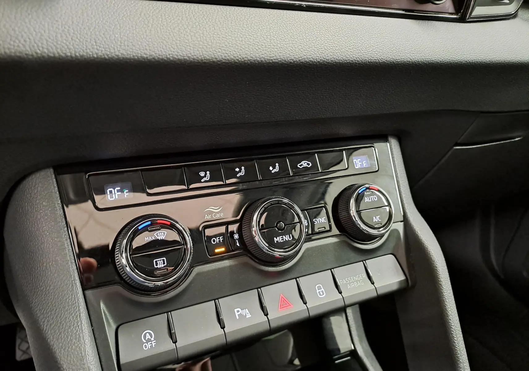 Gros plan sur la console centrale du Skoda Karoq 2023, montrant les commandes de climatisation et les boutons de fonction.
