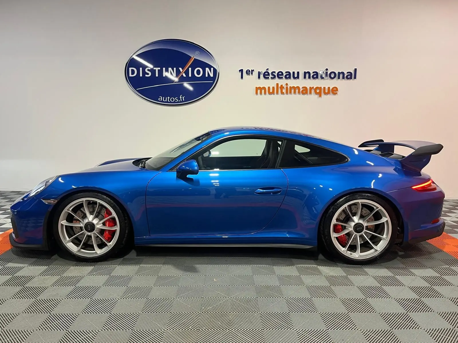Vue de profil côté gauche d'une Porsche 911 GT3 bleu saphir avec aileron arrière et jantes sport argentées.
