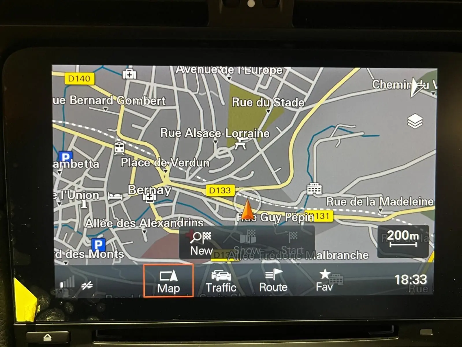 Écran tactile de navigation GPS affichant une carte routière détaillée en intérieur de véhicule.