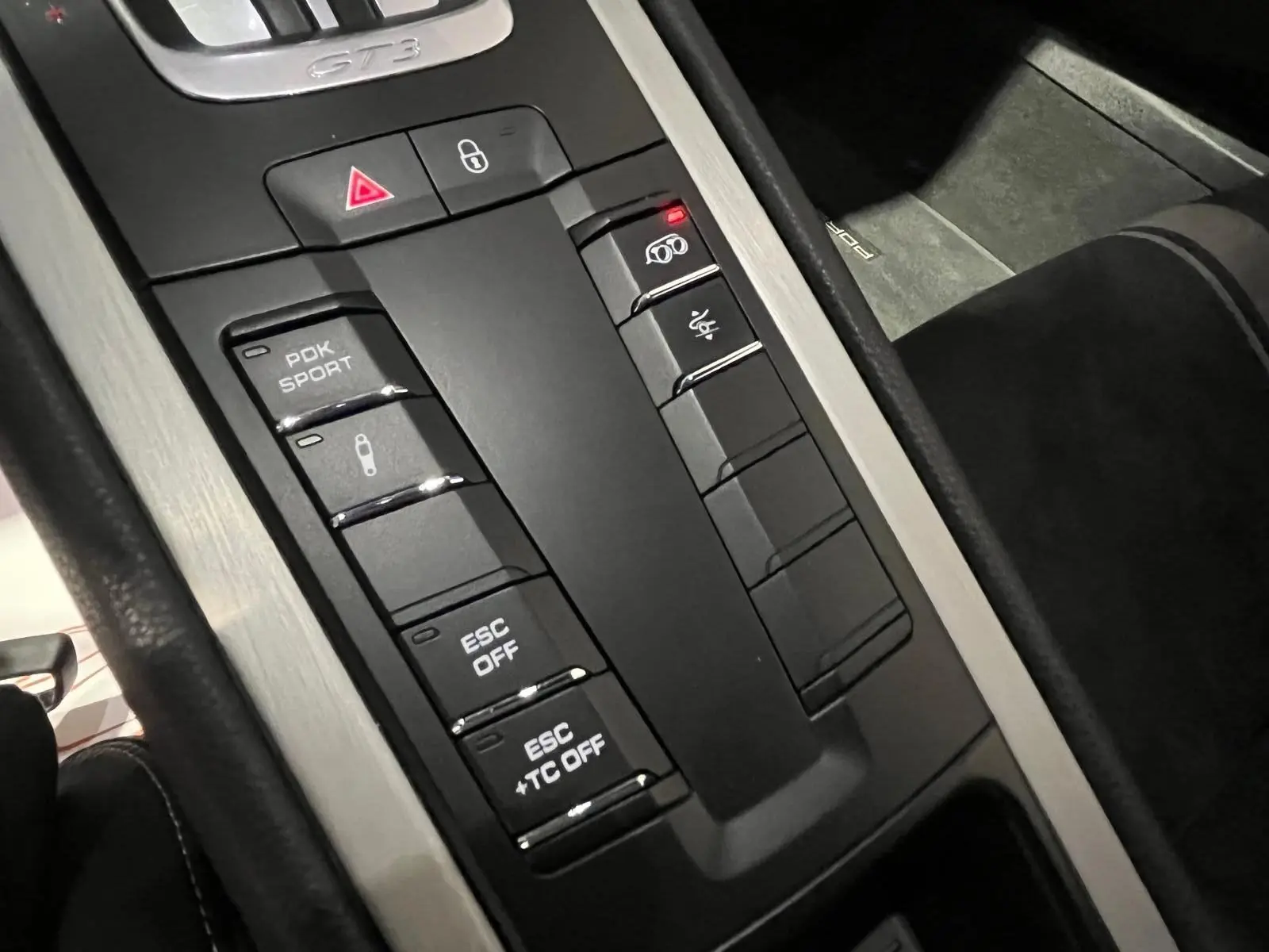 Gros plan sur la console centrale noire et aluminium de la Porsche 911 GT3 bleu saphir, avec boutons sport et GT3 visible.