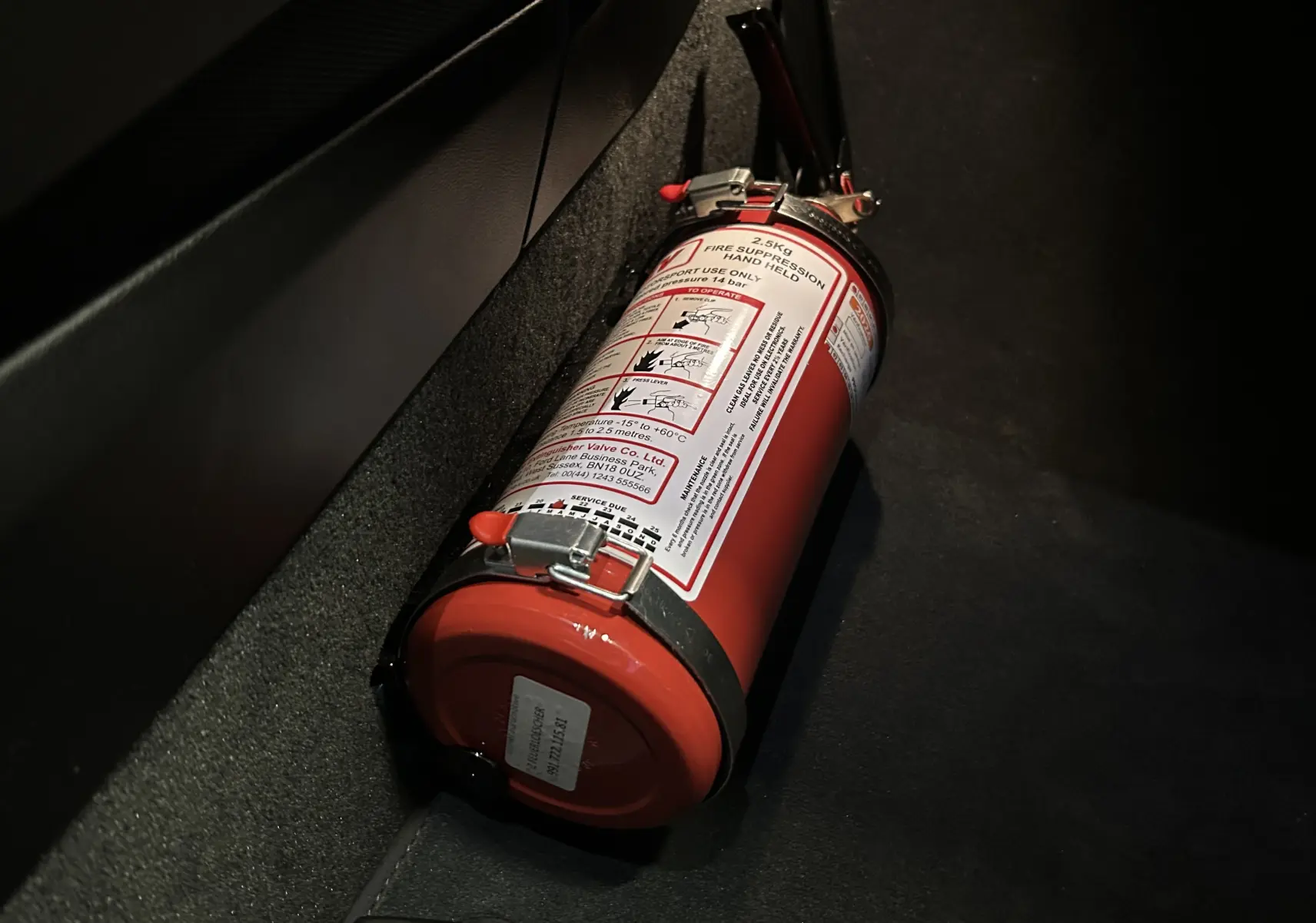 Extincteur rouge fixé au sol sur le tapis noir à l'intérieur de la Porsche 911 GT3 bleu saphir.