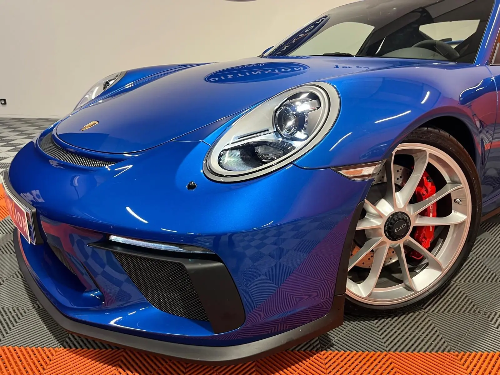 Vue 3/4 avant droit d'une Porsche 911 GT3 bleu saphir avec jantes argentées et étriers de frein rouges.