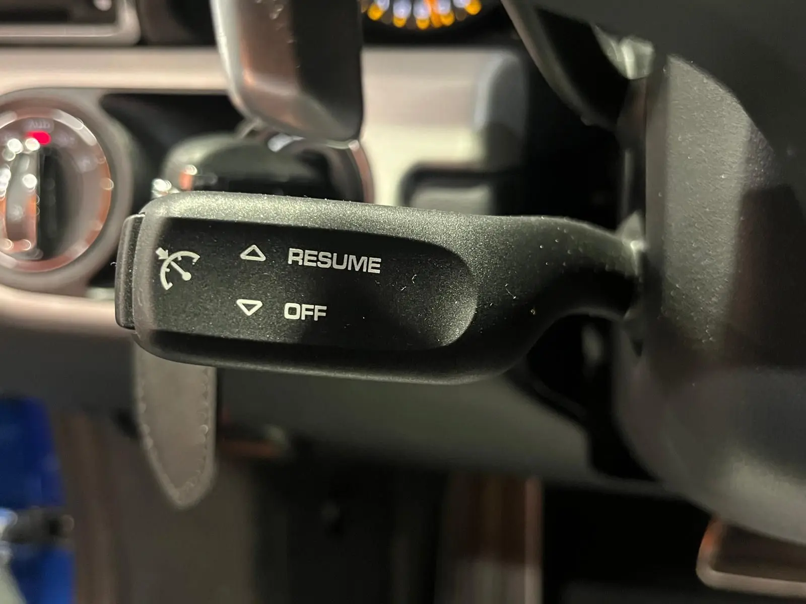 Gros plan sur la commande de régulateur de vitesse à gauche du volant dans l’habitacle d’une Porsche 911 GT3 bleu saphir.