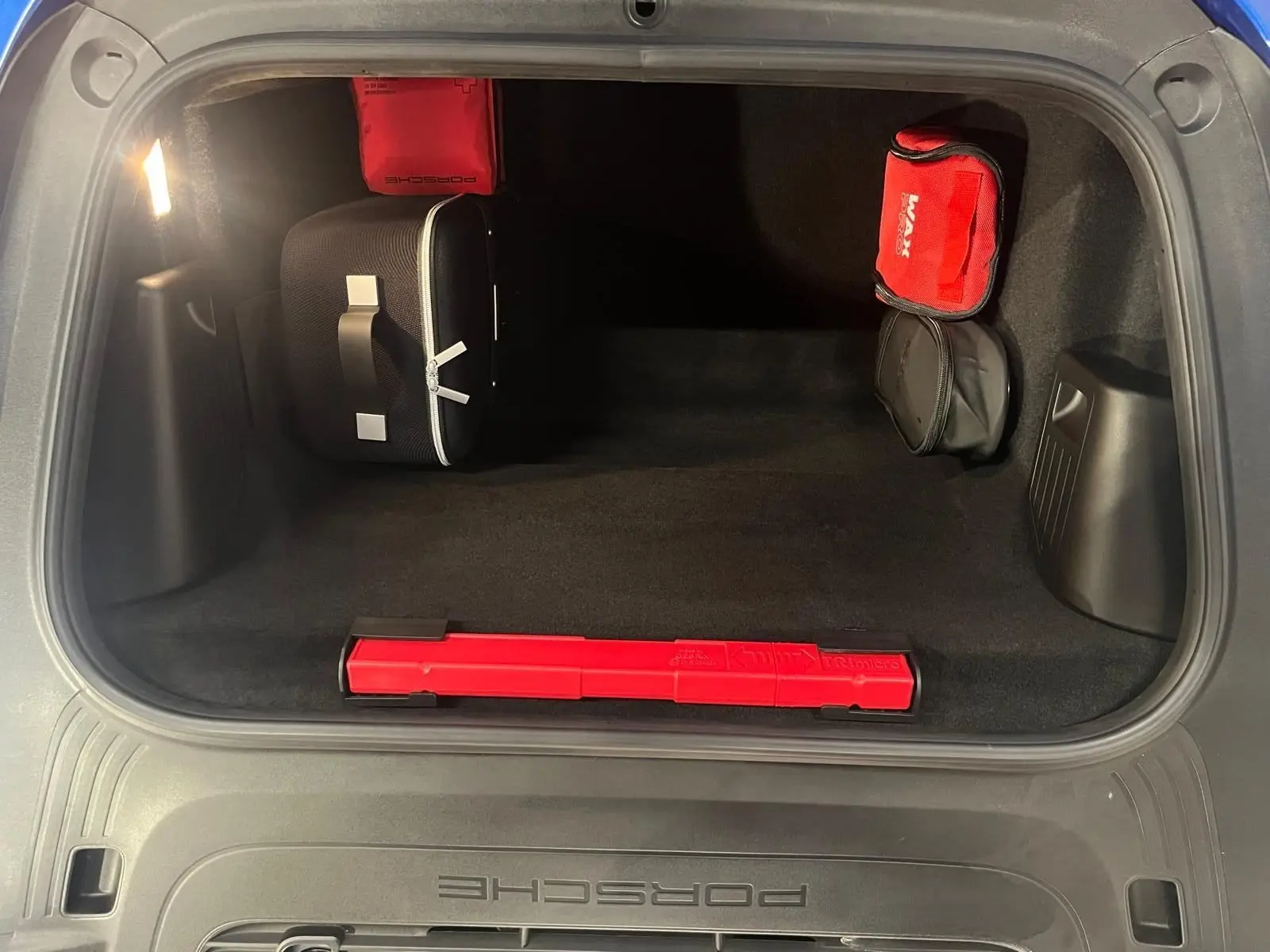 Vue intérieure du coffre avant d'une Porsche 911 GT3 bleu saphir avec trousse de secours et triangle de signalisation rouge.