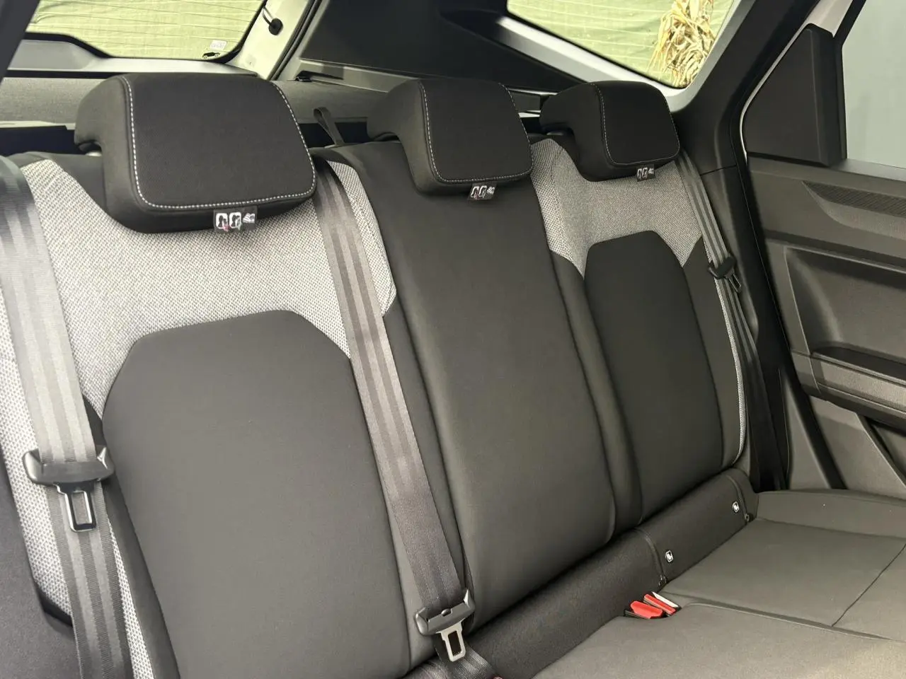 Vue intérieure des sièges arrière en tissu noir et gris du Dacia Bigster 2025, avec appuie-têtes et ceintures visibles.