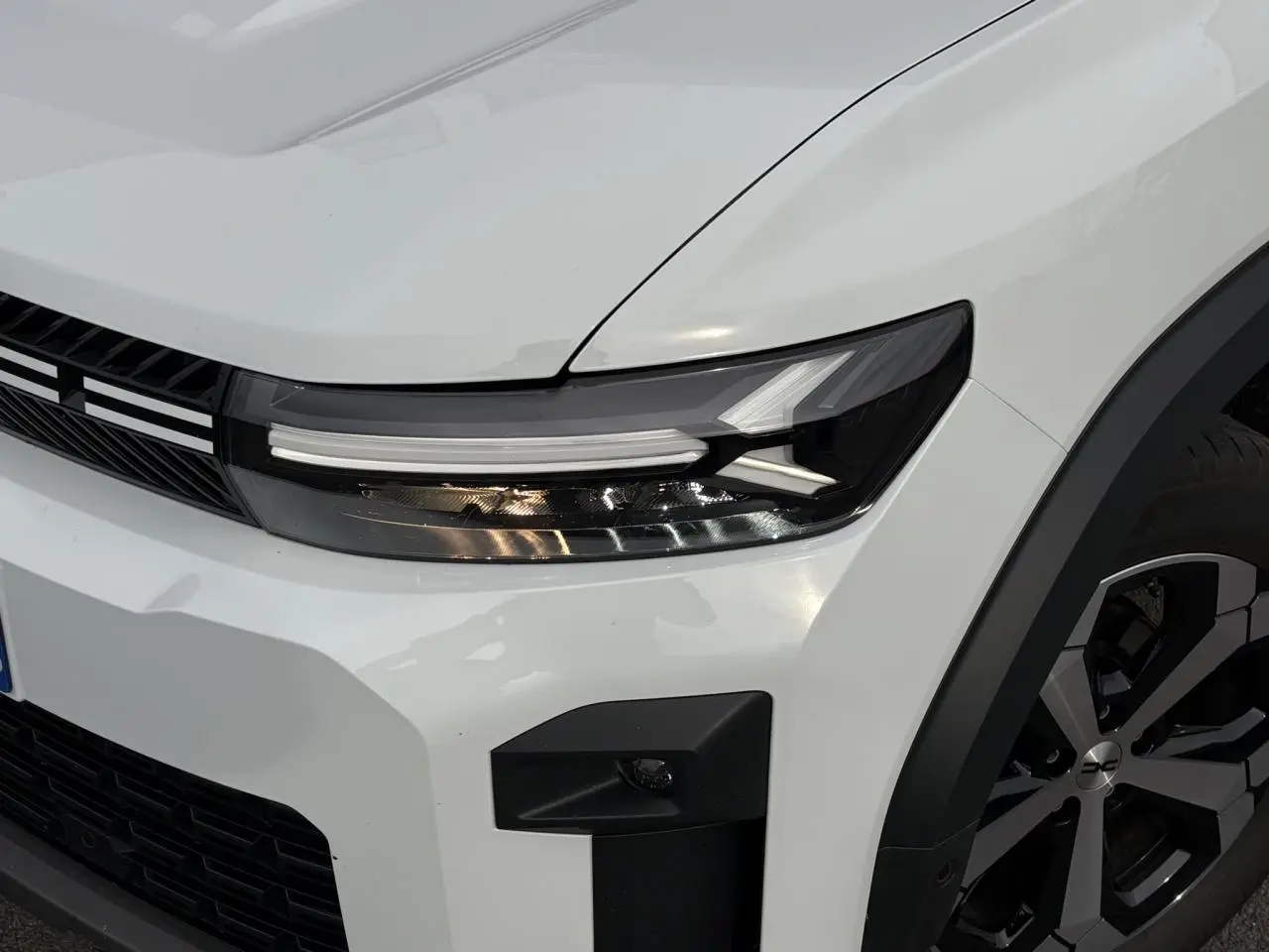 Gros plan sur l'avant droit blanc banquise du Dacia Bigster 2025, avec phare LED et jante alliage diamantée.