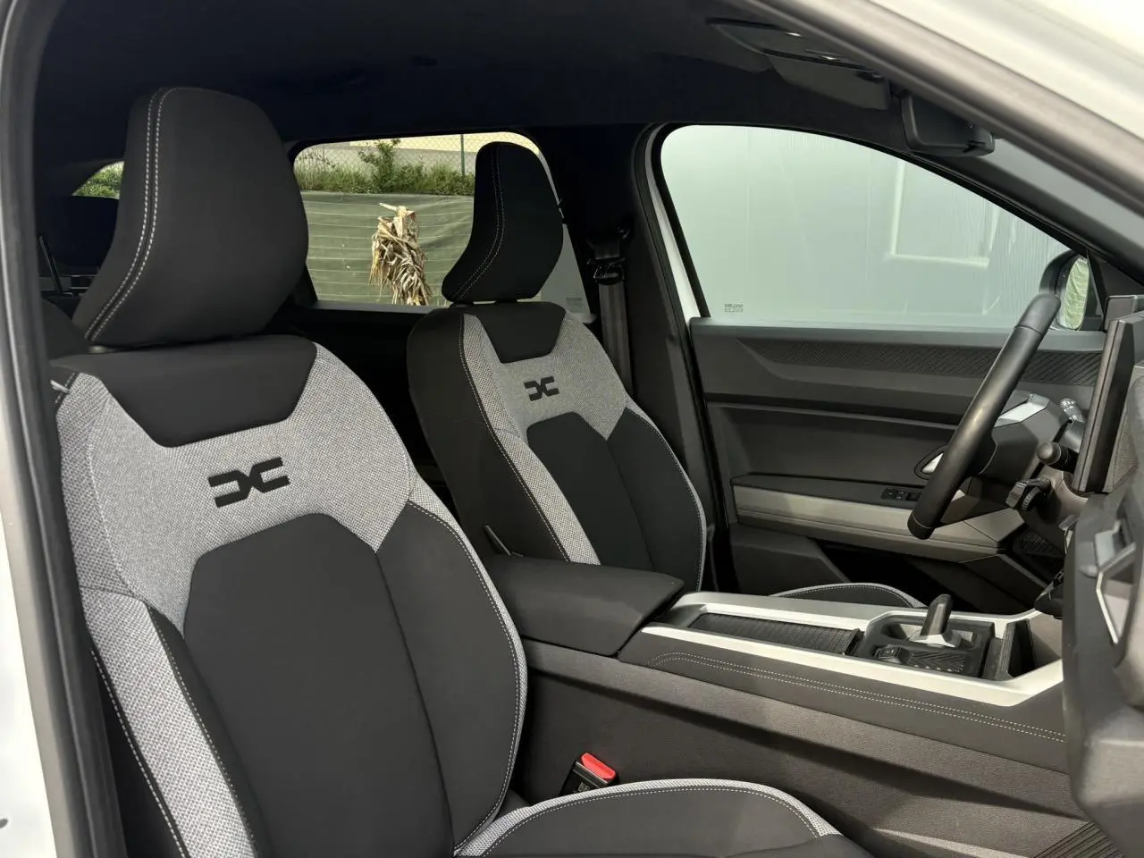 Vue intérieure côté droit montrant les sièges avant gris et noirs avec logo Dacia sur la sellerie du Dacia Bigster 2025.