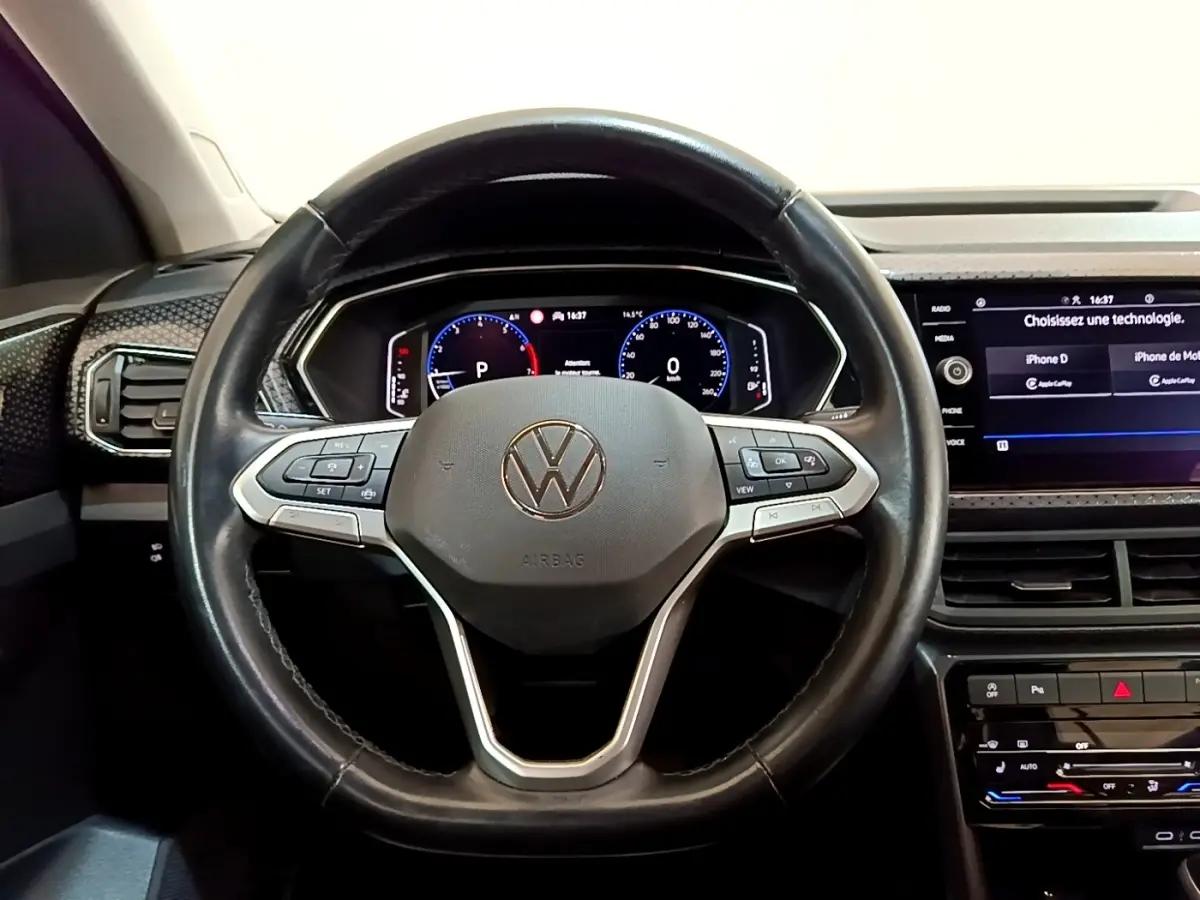 Vue intérieure centrée sur le volant noir en cuir du Volkswagen T-Cross 2022 avec tableau de bord numérique et écran tactile.